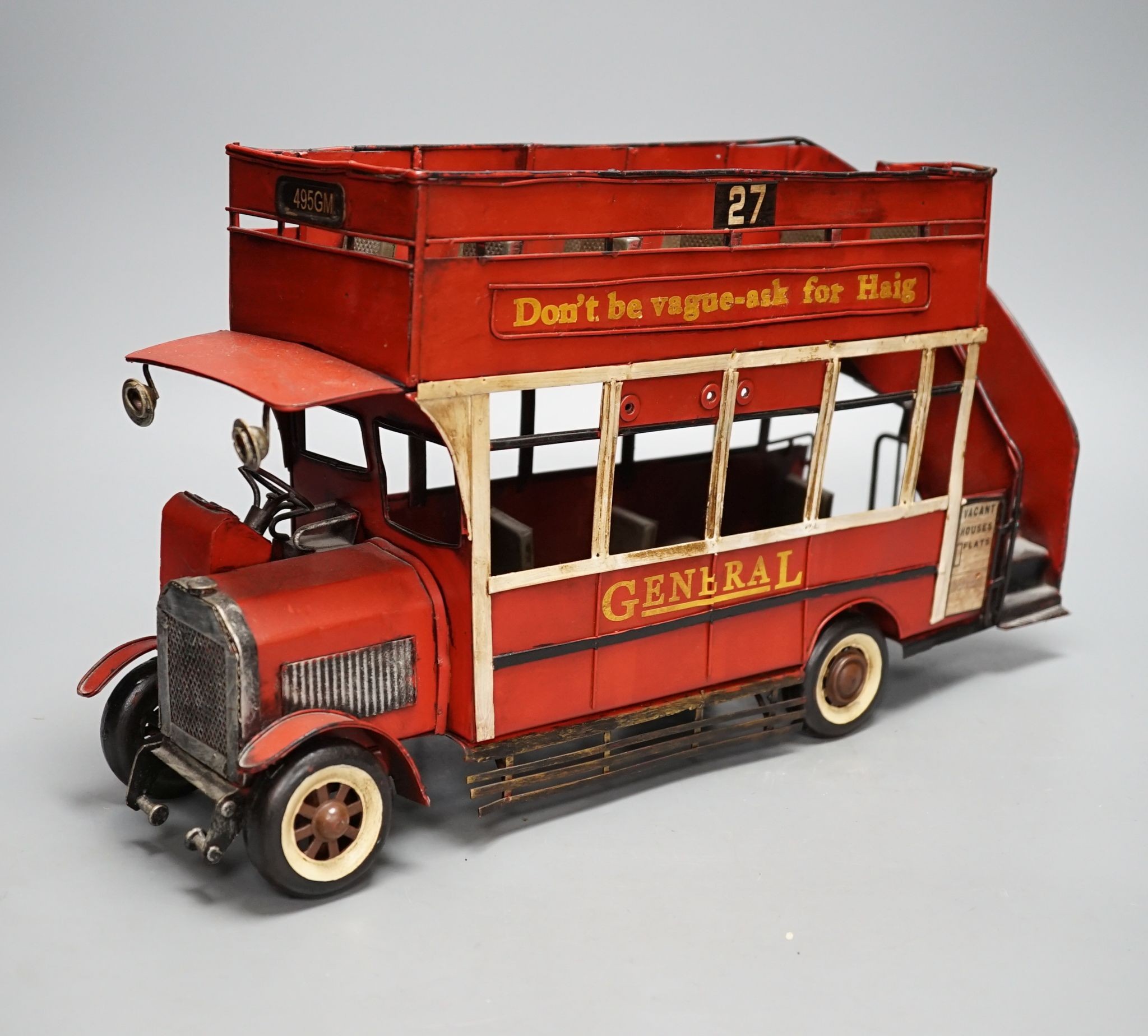 A reproduction tinplate double decker topless bus, the side reading ‘Don’t be vague - ask for Haig’, 42cm long